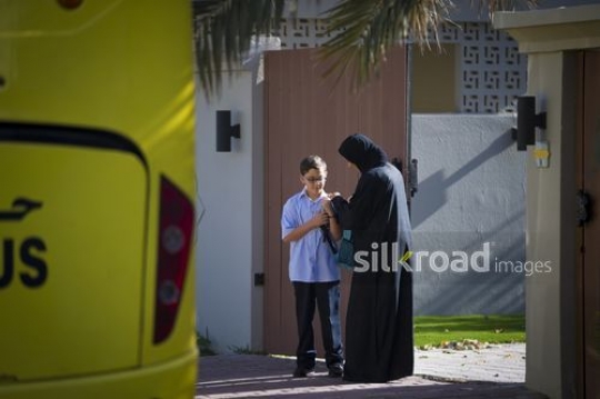 Arab kid giving her son the school bag outside the house|-