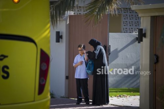 Middle Eastern mother giving her son his school bag|-
