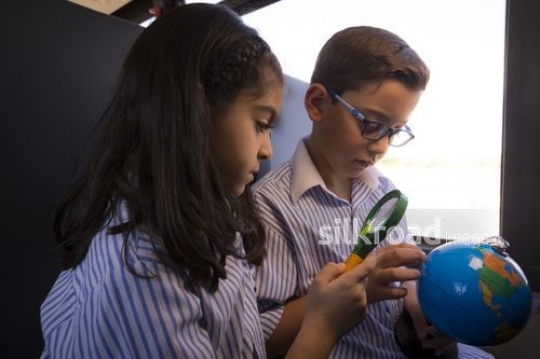 Arab Students looking at the globe through the magnifying glass|-