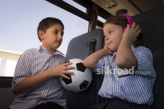 Western Student listening to music next to the Arab student carrying a football|-