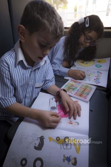 Arab kids sitting together coloring |-