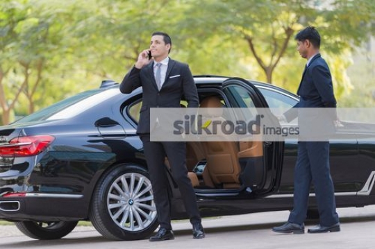 Arab Businessman getting out of the car talking on the phone|