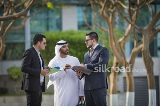 Three Businessmen standing outside talking to each other|-