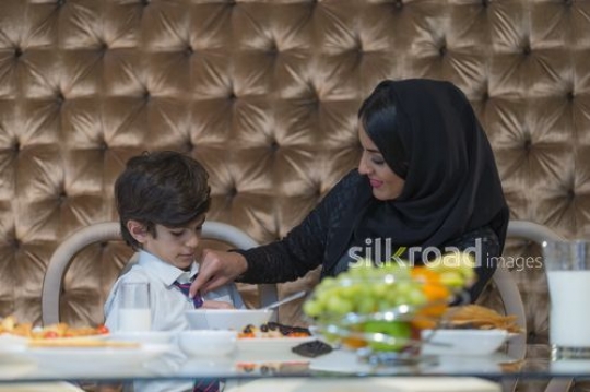 Middle Eastern mom fixing sons tie|