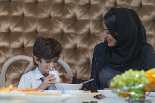 Arab mother helping her son drink milk|-