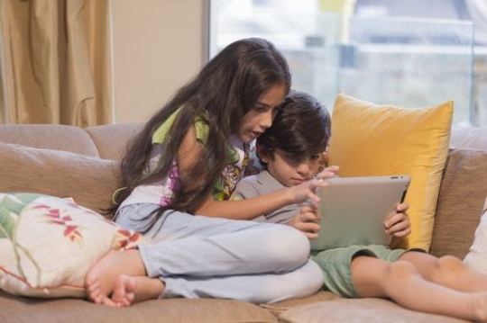Arab boy and girl sitting together playing on the device|-
