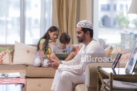 Middle Eastern man and young kids on their devices |