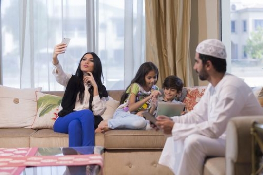 Woman is taking a picture while the man and kids are their tablets|-