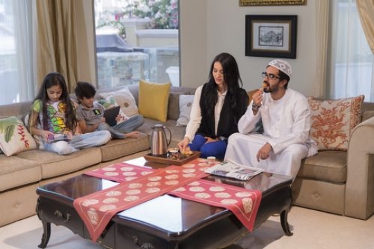 Arab parents sitting together while the kids are on their tablets|-