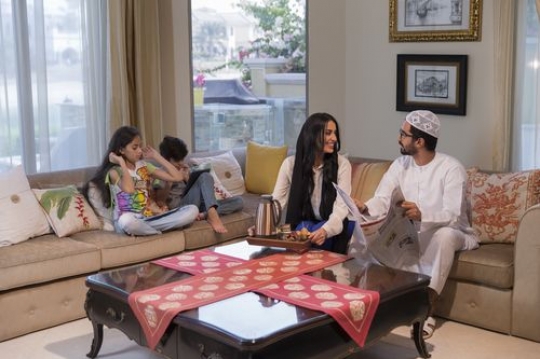 Middle eastern parents sitting together while their kids are on their tablets|-