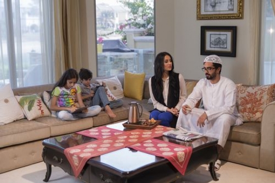 Arab mother and father sitting together while the kids are on their tablet|-
