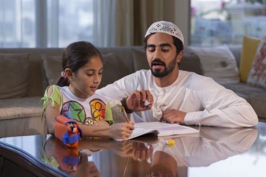 Arab man helping his daughter study|-