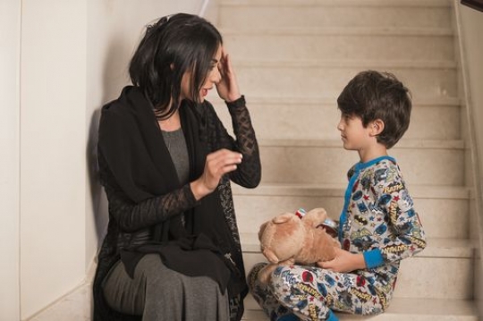 Arab mother and kid sitting on the stairs together|-