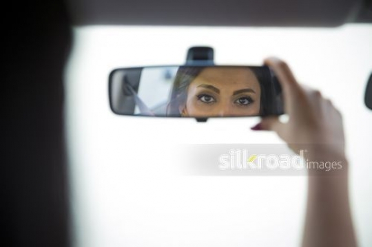 Woman looking at her rear view mirror|-