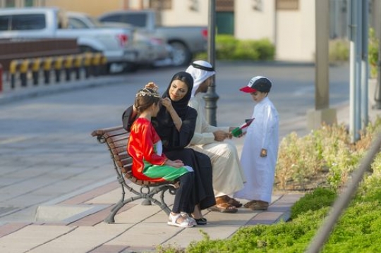 Middle eastern family celebrating national day, the mother is helping her daughter with her traditional head jewellery|-