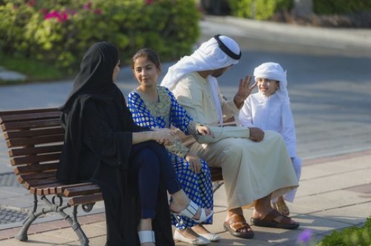 Arab family sitting on the bench talking to each other|-