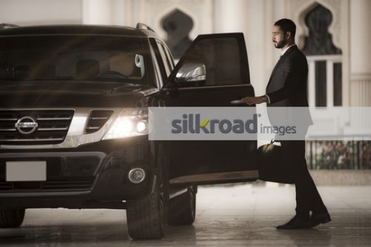 Middle Eastern Businessman closing the door of the car|