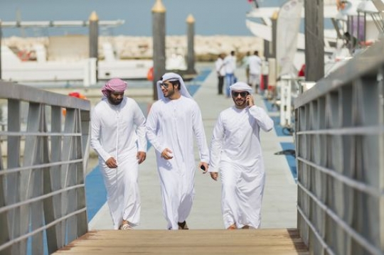 Arab man talking on the phone while walking towards the dock with his friends|