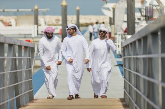 Man having a phone call while walking with his friends towards the dock|