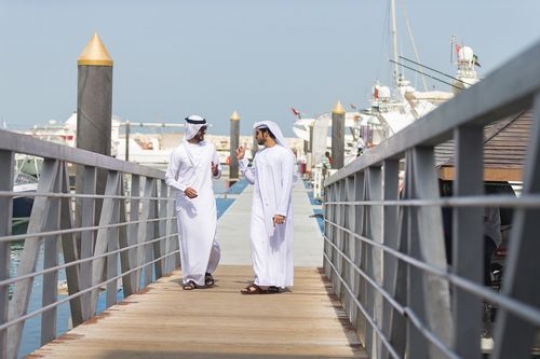 Arabian men walking on the dock talking to each other|