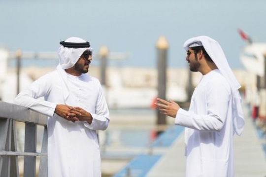 Side view of two men standing by the dock talking to each other|
