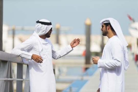 Arabian men standing by the dock talking to each other|