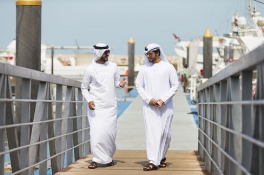 Middle eastern men walking on the dock talking to each other|