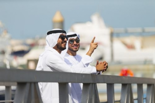 Arab men talking to each other while looking at something|