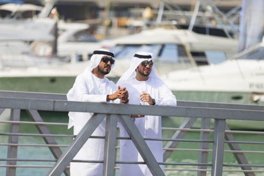 Middle eastern men standing by the dock talking to each other|