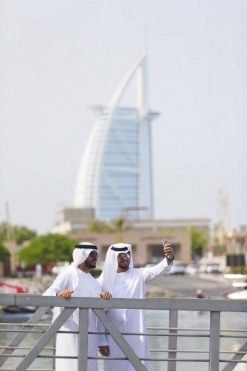 Arab men standing by the dock taking a picture together with a background of a well-known landmark|