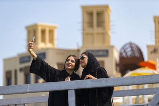 Women dressed in the traditional UAE attire standing by the dock taking a picture together|