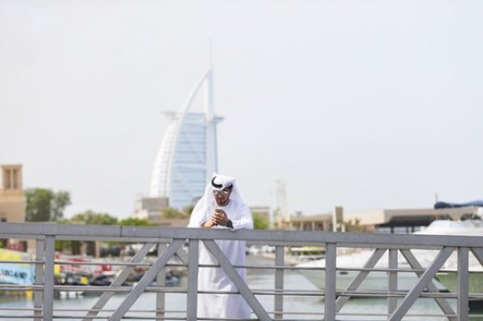 Arabian man standing by the dock with a background of a well-known landmark |