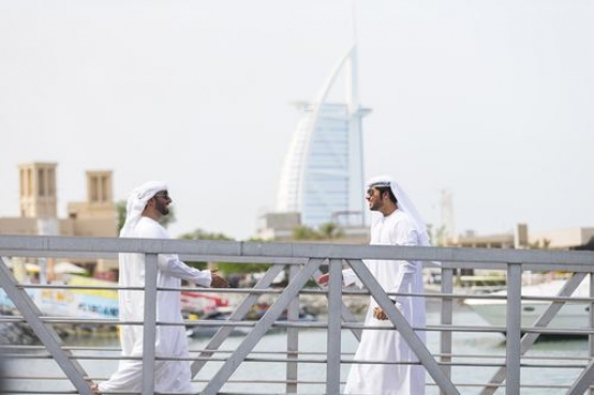 Arab man walking towards his friend whose standing by the dock|