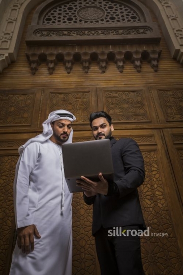 Arab Businessman standing with his colleague using the laptop|-
