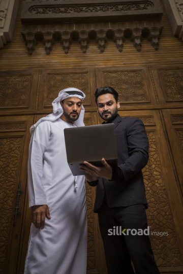 Businessmen standing together using the laptop|-