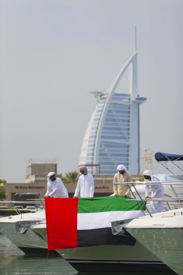 Arab men attaching the UAE flag to the yacht to represent their country|