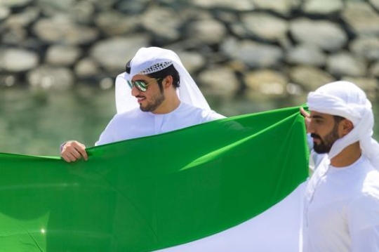 Arab men holding a UAE Flag to represent their country during National Day|