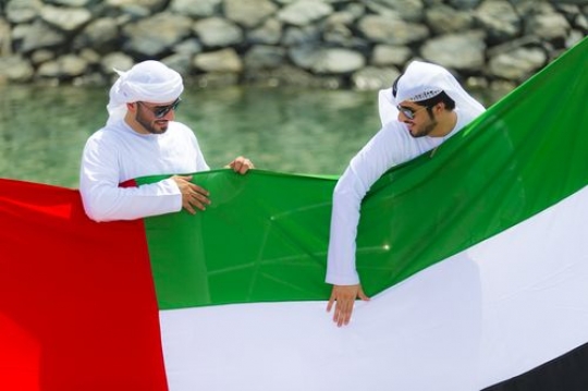Arabian men holding the UAE flag during the celebrations of National Day|