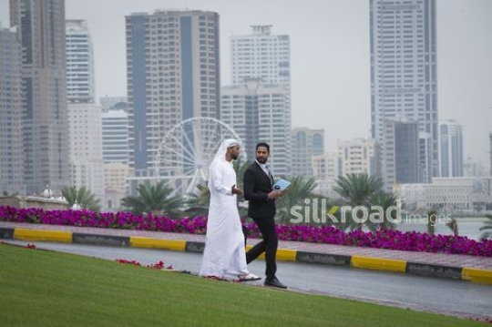 Businessman carrying folders walking with his colleague outside|-