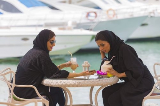 Women sitting outside and talking to each other while having cold drinks|