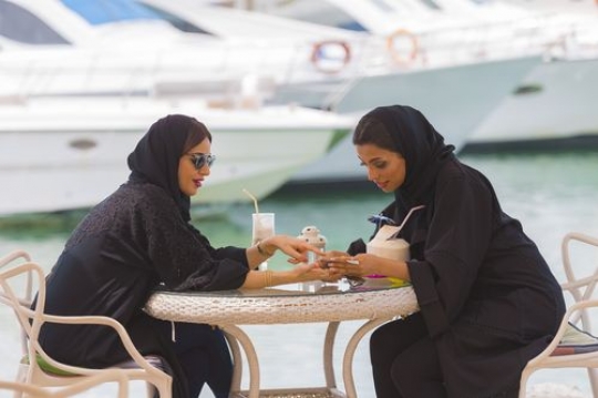 Female friends sitting and talking to each other while looking at something|