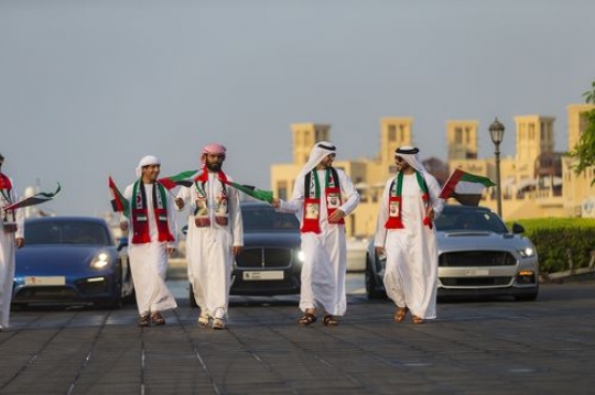 Arab men dressed in the traditional attire followed by luxurious cars during the National Day Parade|-