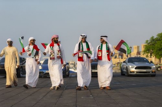 Luxury cars and Emirati men during a National Day Parade|-