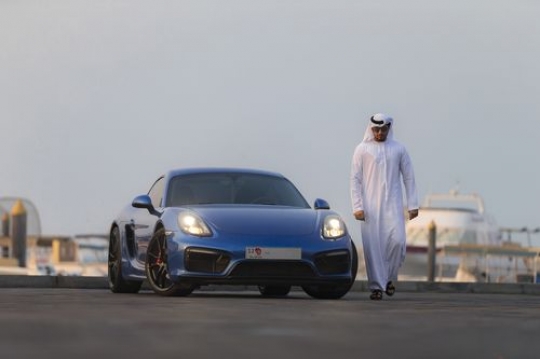 Arab man in motion walking away from his vehicle while dressed in the UAE traditional attire|-