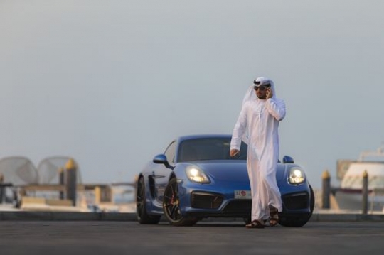 Arab man talking on the phone while walking away from parked car|-