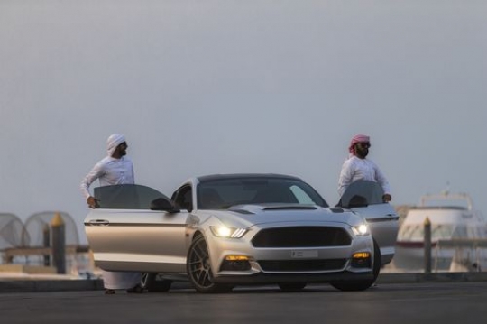 Arab men dressed in the UAE traditional attire exiting the vehicle|-
