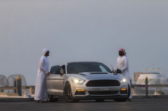 Two arab men dressed in traditional attire are opening the doors of the car|-