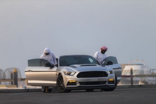Two arab men dressed in traditional attire are entering the car|-