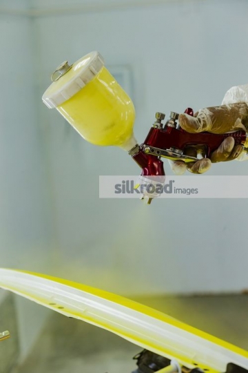 Mechanic spray painting the part of the car|