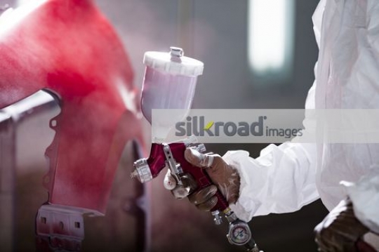 Spray painting a part of the car red|